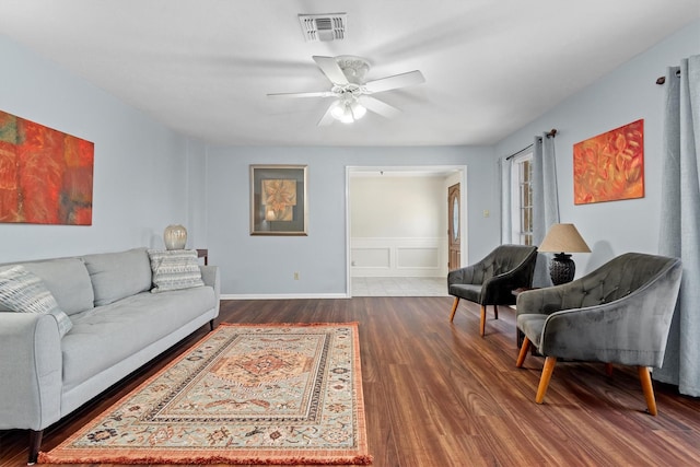 living area featuring a decorative wall, wood finished floors, visible vents, and a ceiling fan