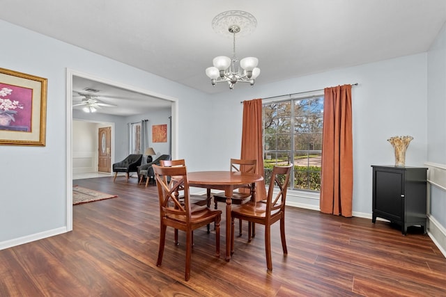 dining space with dark wood-type flooring, baseboards, and ceiling fan with notable chandelier