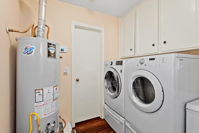 washroom featuring dark wood-type flooring, water heater, cabinet space, and washing machine and clothes dryer