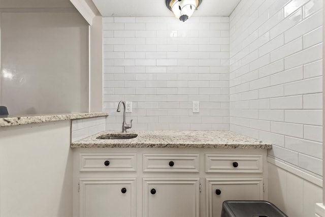 kitchen with a sink, white cabinets, and light stone countertops