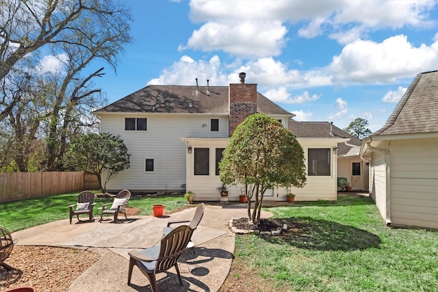 rear view of house featuring a chimney, a lawn, a patio area, and fence