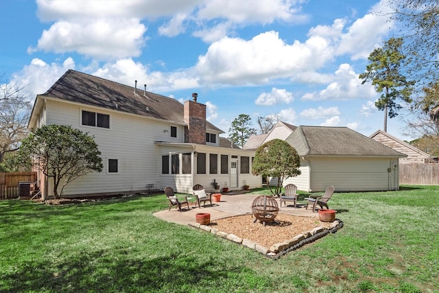 rear view of house featuring a chimney, a lawn, an outdoor fire pit, a sunroom, and fence