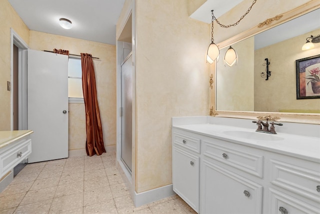 bathroom featuring baseboards, a shower stall, and vanity