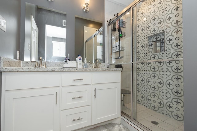 bathroom with double vanity, a shower stall, visible vents, and a sink