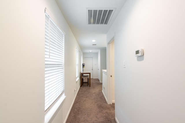 corridor with carpet, visible vents, and baseboards