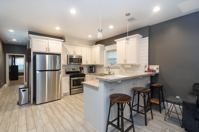 kitchen with visible vents, decorative backsplash, appliances with stainless steel finishes, a breakfast bar, and a sink