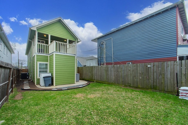 rear view of house with a yard, a fenced backyard, and a balcony