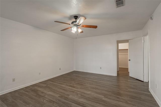 spare room with dark wood-style floors, ceiling fan, visible vents, and baseboards