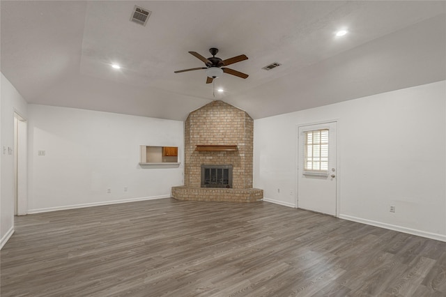 unfurnished living room with dark wood-style flooring, a fireplace, visible vents, vaulted ceiling, and ceiling fan