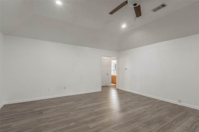 empty room featuring ceiling fan, visible vents, baseboards, vaulted ceiling, and dark wood finished floors