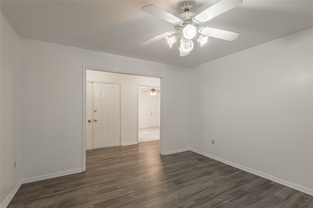 empty room with ceiling fan, dark wood-type flooring, and baseboards