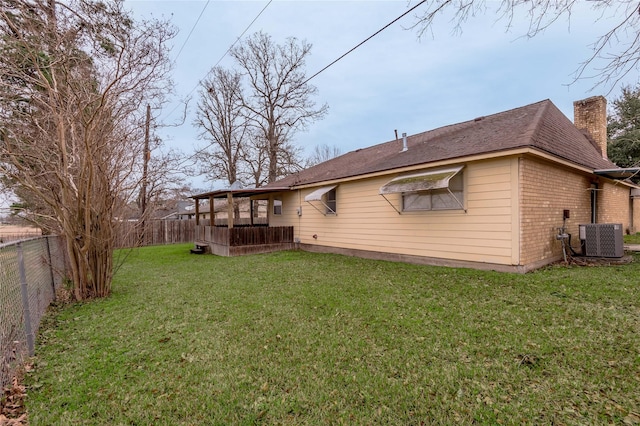 back of property featuring central AC unit, a lawn, a fenced backyard, a chimney, and brick siding