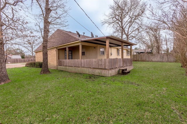 view of side of property with a yard, brick siding, a shingled roof, and fence