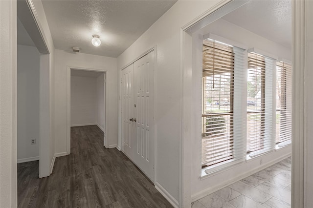 hall with a textured ceiling, a wealth of natural light, and baseboards