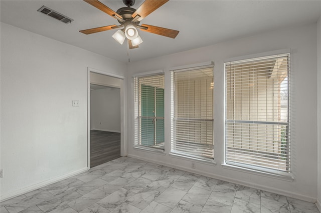 unfurnished room featuring marble finish floor, baseboards, visible vents, and a ceiling fan