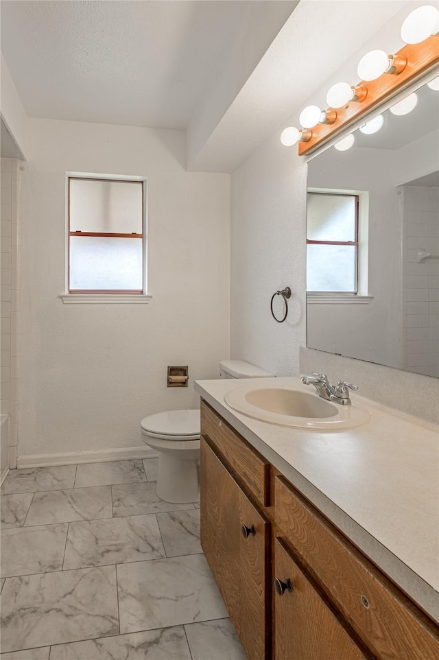 full bathroom with toilet, marble finish floor, baseboards, and vanity