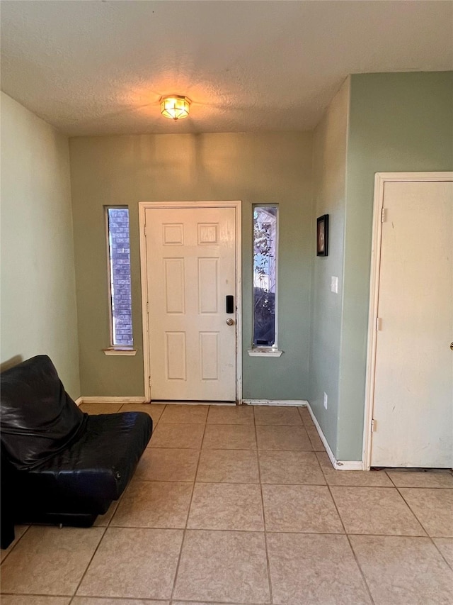 foyer with light tile patterned floors, baseboards, and a textured ceiling