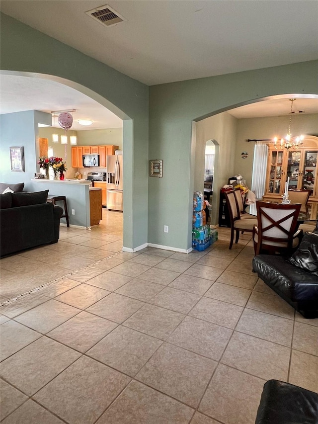 living room with light tile patterned floors, arched walkways, visible vents, and a notable chandelier