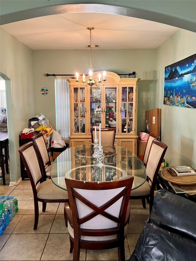 dining space featuring light tile patterned floors, arched walkways, and a notable chandelier