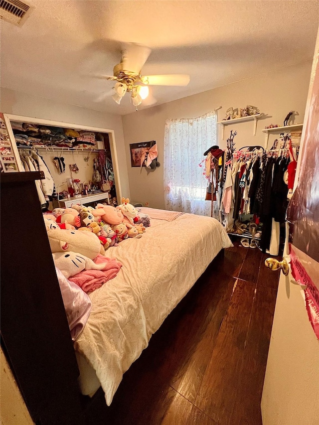 bedroom featuring ceiling fan, a textured ceiling, visible vents, and wood finished floors