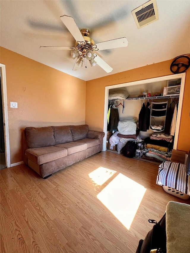 living room featuring visible vents, ceiling fan, and wood finished floors