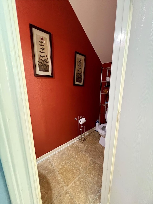 bathroom featuring lofted ceiling, tile patterned flooring, toilet, and baseboards