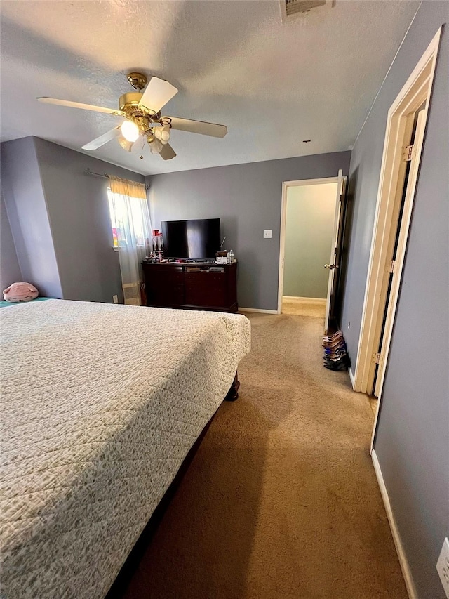 bedroom featuring a textured ceiling, baseboards, a ceiling fan, and light colored carpet