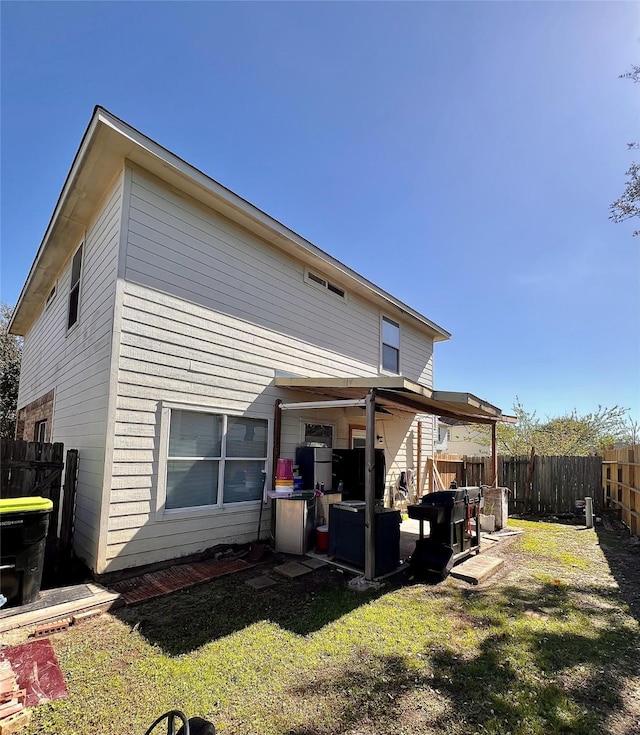 back of house with a patio area, a fenced backyard, and a lawn