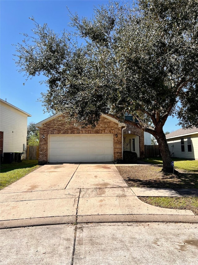 view of front facade with a garage, brick siding, driveway, and fence