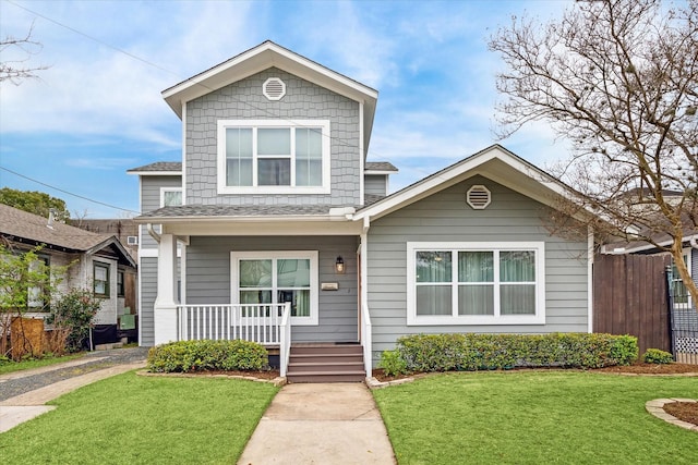 view of front of property with a porch, fence, and a front lawn