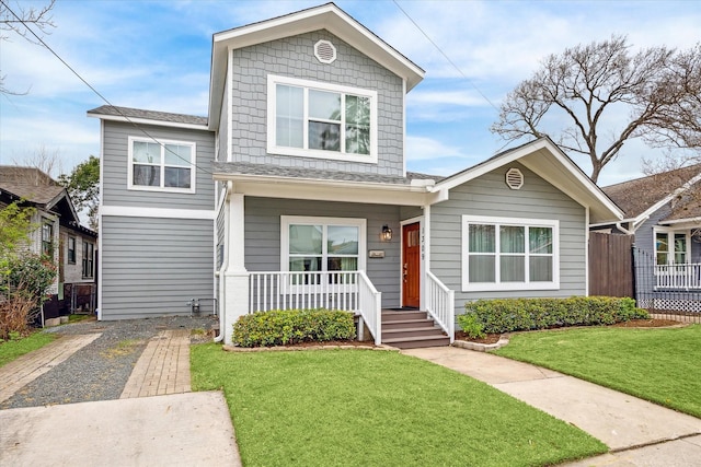 view of front of house featuring driveway, covered porch, and a front lawn