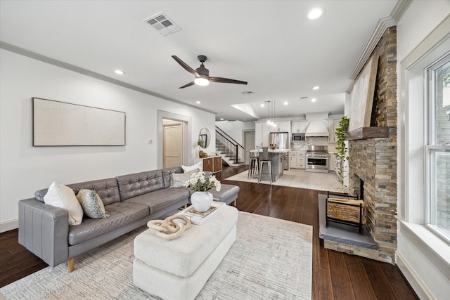 living area with hardwood / wood-style flooring, visible vents, crown molding, and stairs