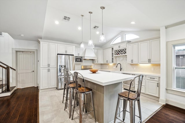 kitchen featuring visible vents, appliances with stainless steel finishes, a breakfast bar, and a center island