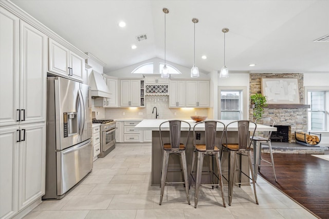 kitchen with visible vents, lofted ceiling, a breakfast bar area, stainless steel appliances, and light countertops