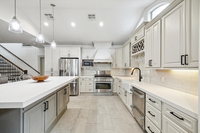 kitchen with premium range hood, visible vents, appliances with stainless steel finishes, and a sink