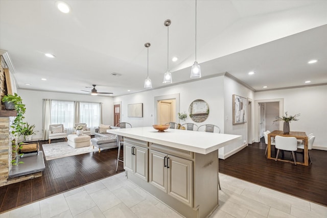 kitchen with a kitchen island, a kitchen breakfast bar, vaulted ceiling, light countertops, and crown molding