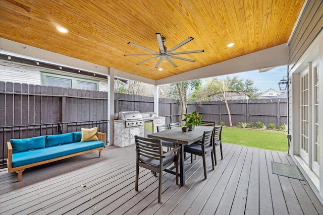 deck with outdoor dining area, a fenced backyard, ceiling fan, and area for grilling