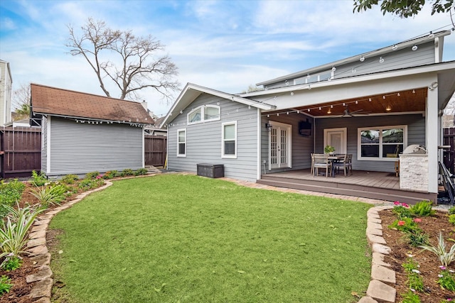 rear view of property featuring french doors, ceiling fan, an outbuilding, fence, and a wooden deck