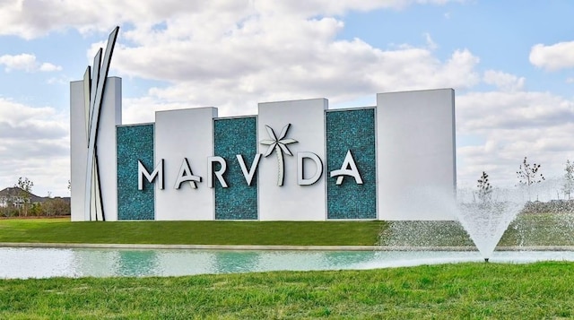 community / neighborhood sign featuring a water view and a lawn