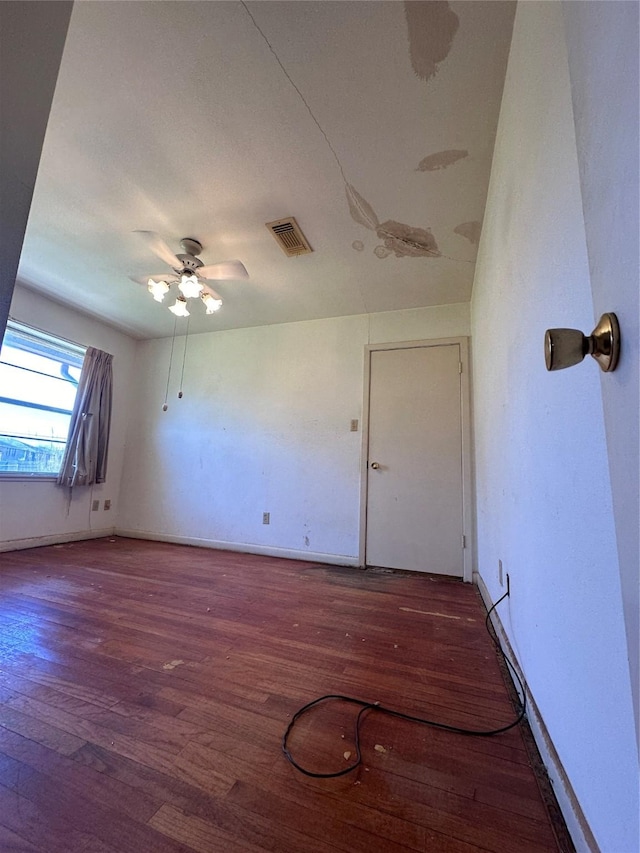 empty room featuring ceiling fan, wood finished floors, visible vents, and baseboards