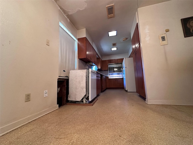 kitchen featuring baseboards, visible vents, and freestanding refrigerator