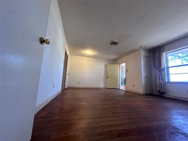 spare room featuring visible vents, baseboards, and wood finished floors