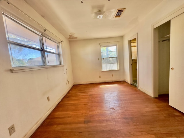 unfurnished bedroom with a closet, wood finished floors, visible vents, and baseboards