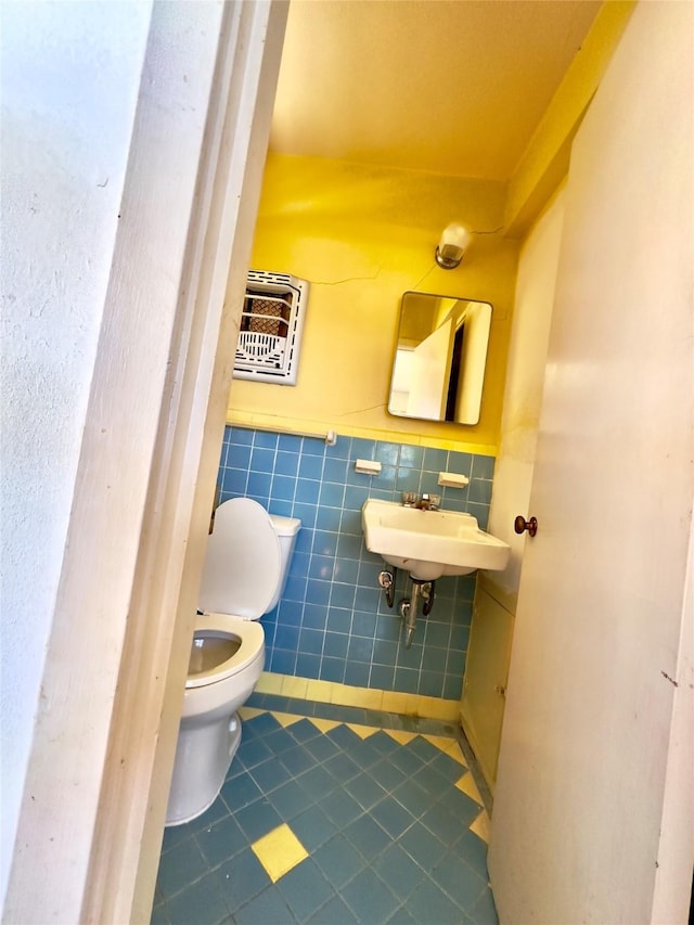 bathroom featuring toilet, a wainscoted wall, tile patterned floors, tile walls, and heating unit