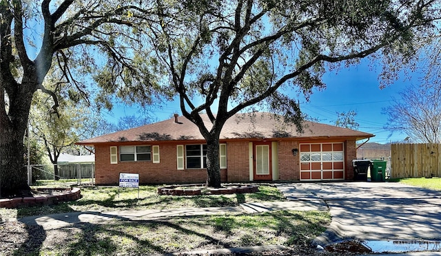 ranch-style house featuring a garage, driveway, brick siding, and fence