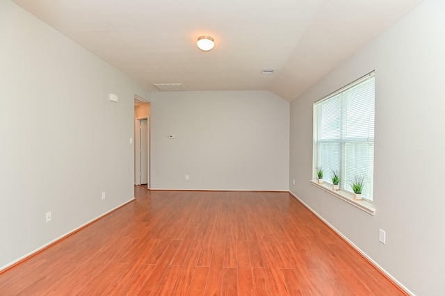 unfurnished room featuring visible vents, baseboards, vaulted ceiling, and light wood finished floors