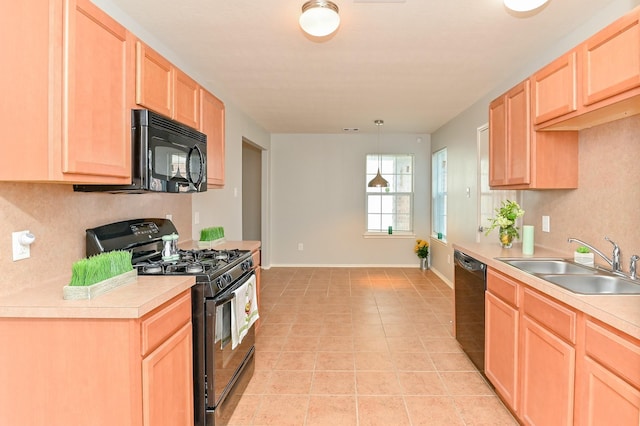 kitchen featuring light brown cabinets, baseboards, light countertops, black appliances, and a sink