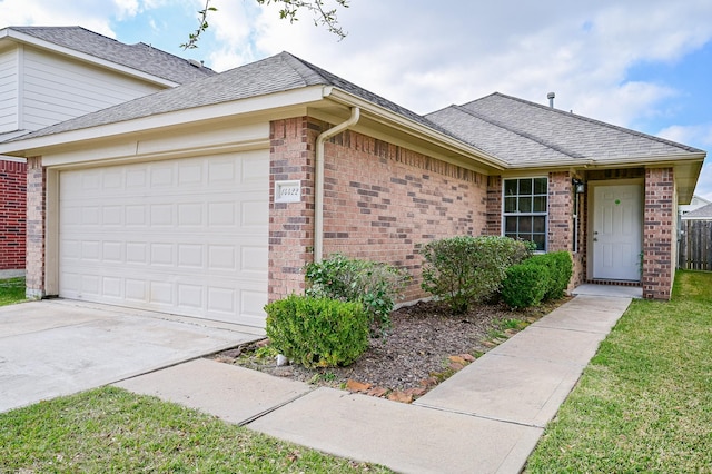 single story home featuring roof with shingles, an attached garage, concrete driveway, a front lawn, and brick siding