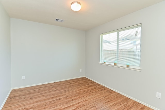 empty room featuring baseboards, visible vents, and light wood finished floors