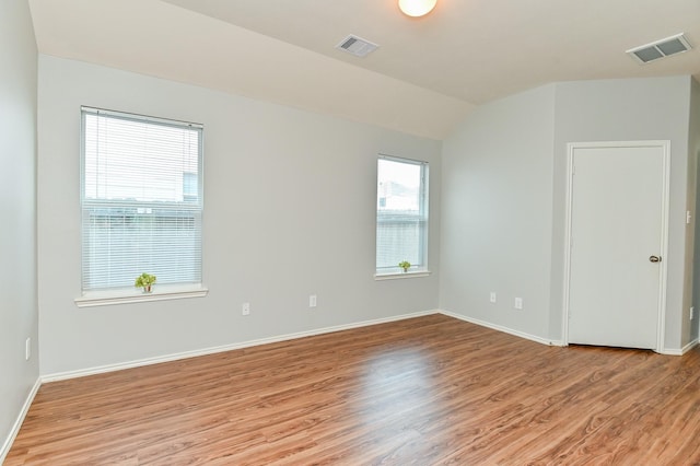 spare room featuring vaulted ceiling, baseboards, visible vents, and light wood-type flooring